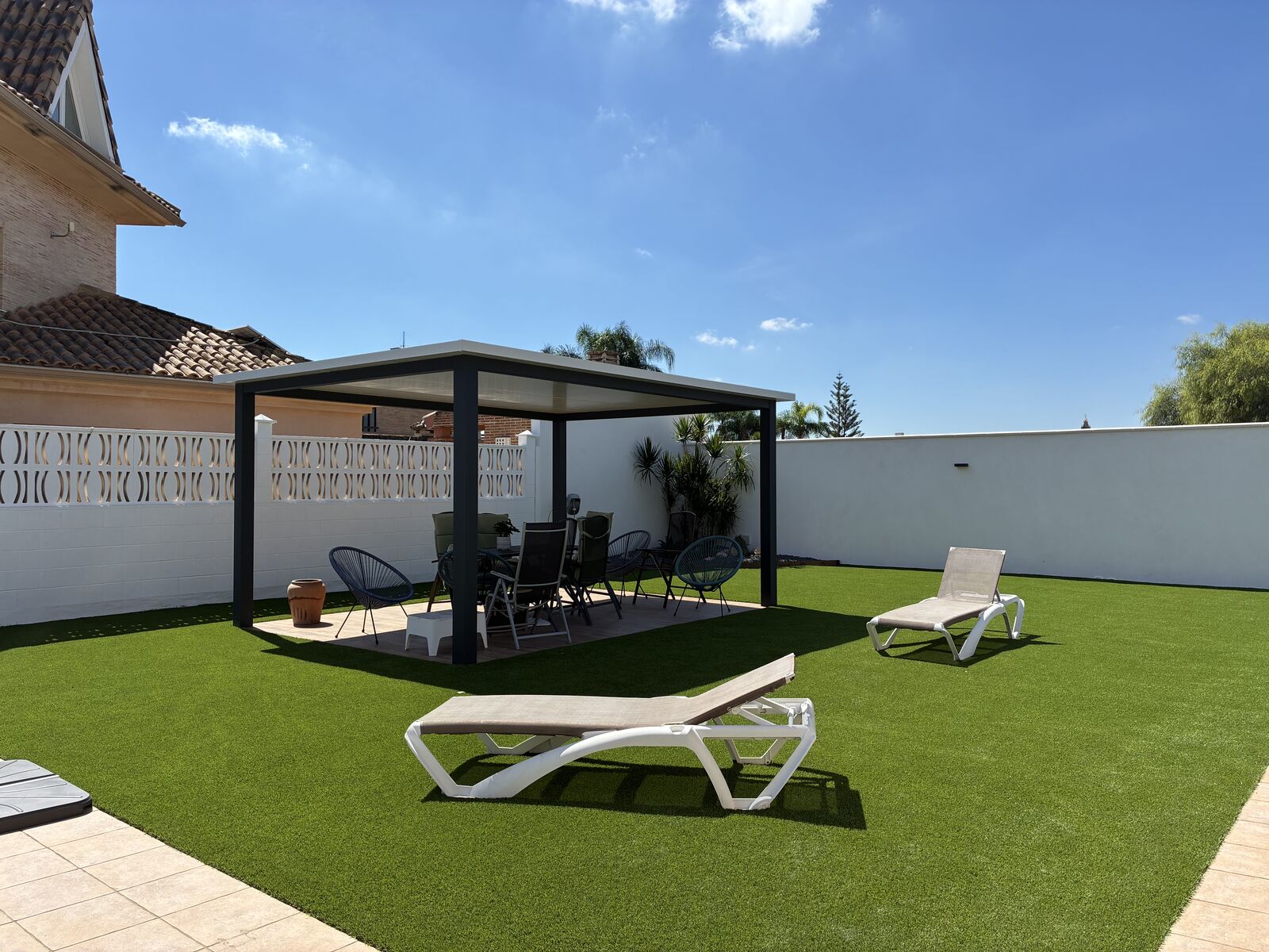 Jardín con pérgola y césped artificial